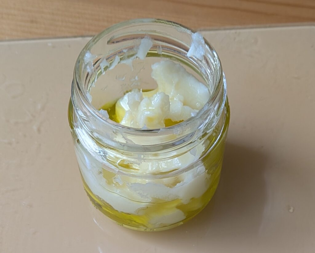 Olive oil and shea butter in a small jar.