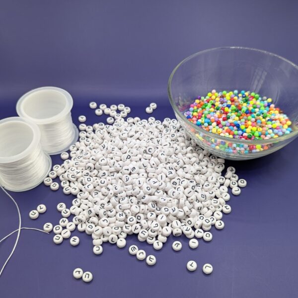 Two rolls of jewelry elastic, a pile of about 1000 plastic Hebrew beads, and a glass bowl of pastel filler beads.